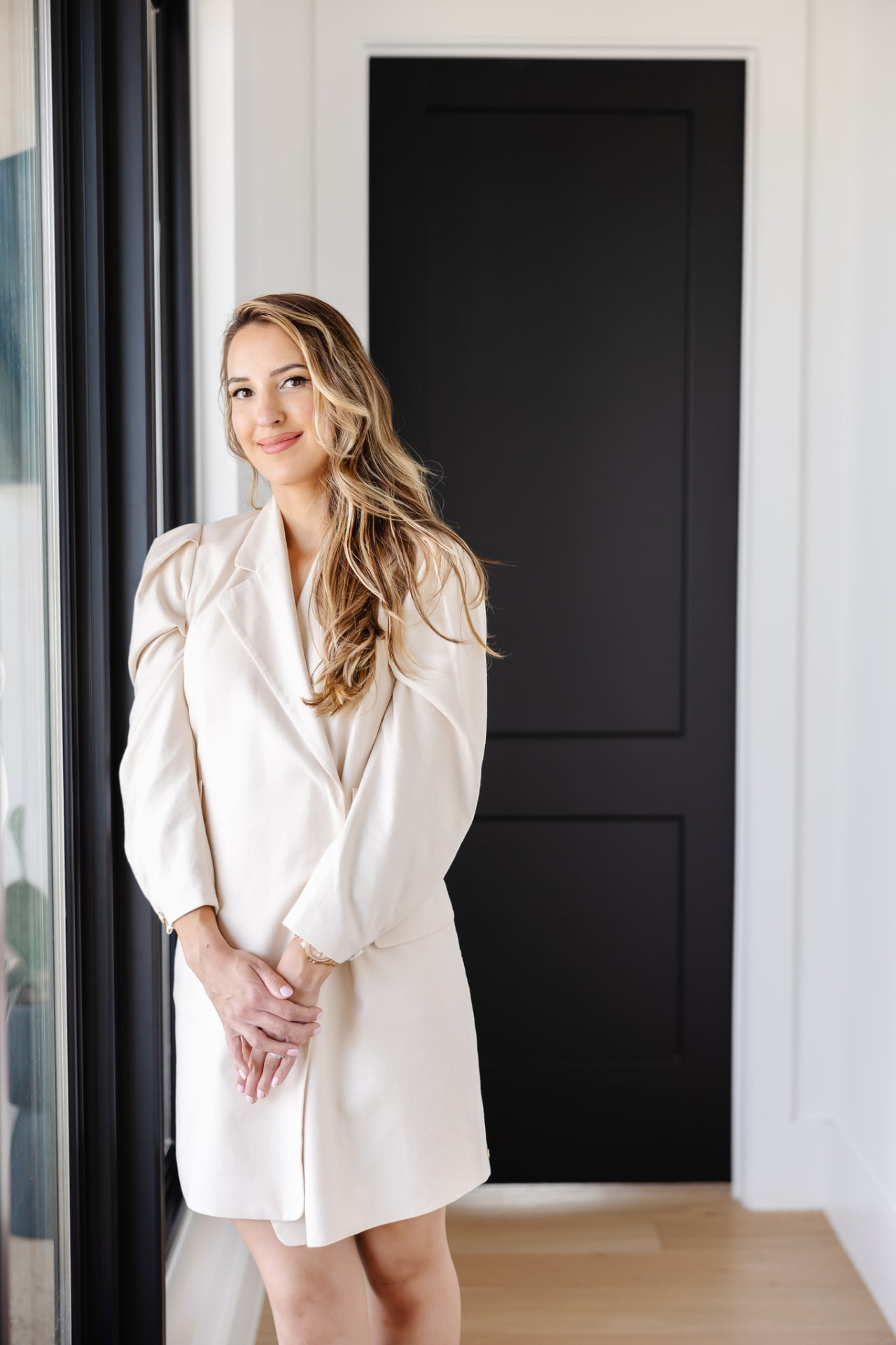 Emilia Williams, founder of Segovias, smiling in a cream blazer dress at home